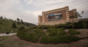 A Deadwood sign just outside of town with a stagecoach on it.