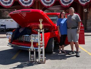 Kool Deadwood Nites Classic Car Show top car is a 1964 red Ford F100. Pictured with the owner and trophies.