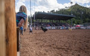 Woman watches as bull rider tries to hang on