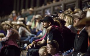 The audience watches the next cowboy gets ready to ride