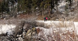 A happy couple walks down a snow covered trail in the winter