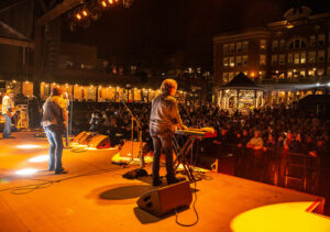 A band plays an evening performance at Outlaw Square in Deadwood, SD. Crows is gathered in the square, on the street behind it, the Franklin balcony, and the Veranda at the Silverado.