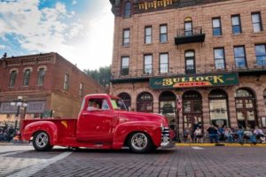 Classic red truck driving down main street for Kool Deadwood Nites event