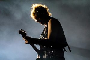 Man playing electric guitar on foggy stage