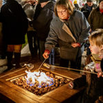 People roasting marshmallows on an outdoor fireplace.