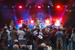 Photo of Outlaw Square stage during a night-time concert. Redan and blue lights cover the stage.