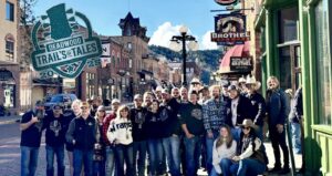 Picture of a large group of people on Deadwood main street on a sunny day.