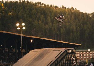 Photo of a racer in the middle of a jump on a dirtbike over an inflatable ramp.