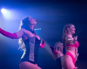 picture of three women dressed in revealing costumes performing a dance on a stage.