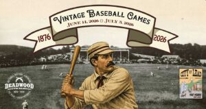 A black and white historic photo of a baseball game with a vintage-style player winding up for a swing. The banner on top says "Vintage Baseball Game"